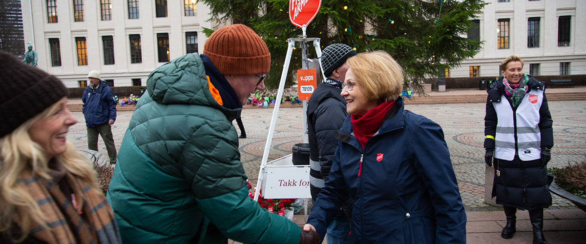 Mester Grønn gir penger til Frelsesarmeen